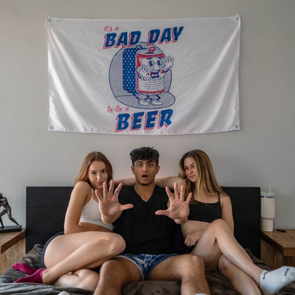 Three college friends posing with a witty 'It's a BAD DAY to be a BEER' dorm room flag.