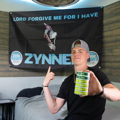 College student holding stacked zyn nicotine puch containers in front of a humorous zyn themed wall flag decoration