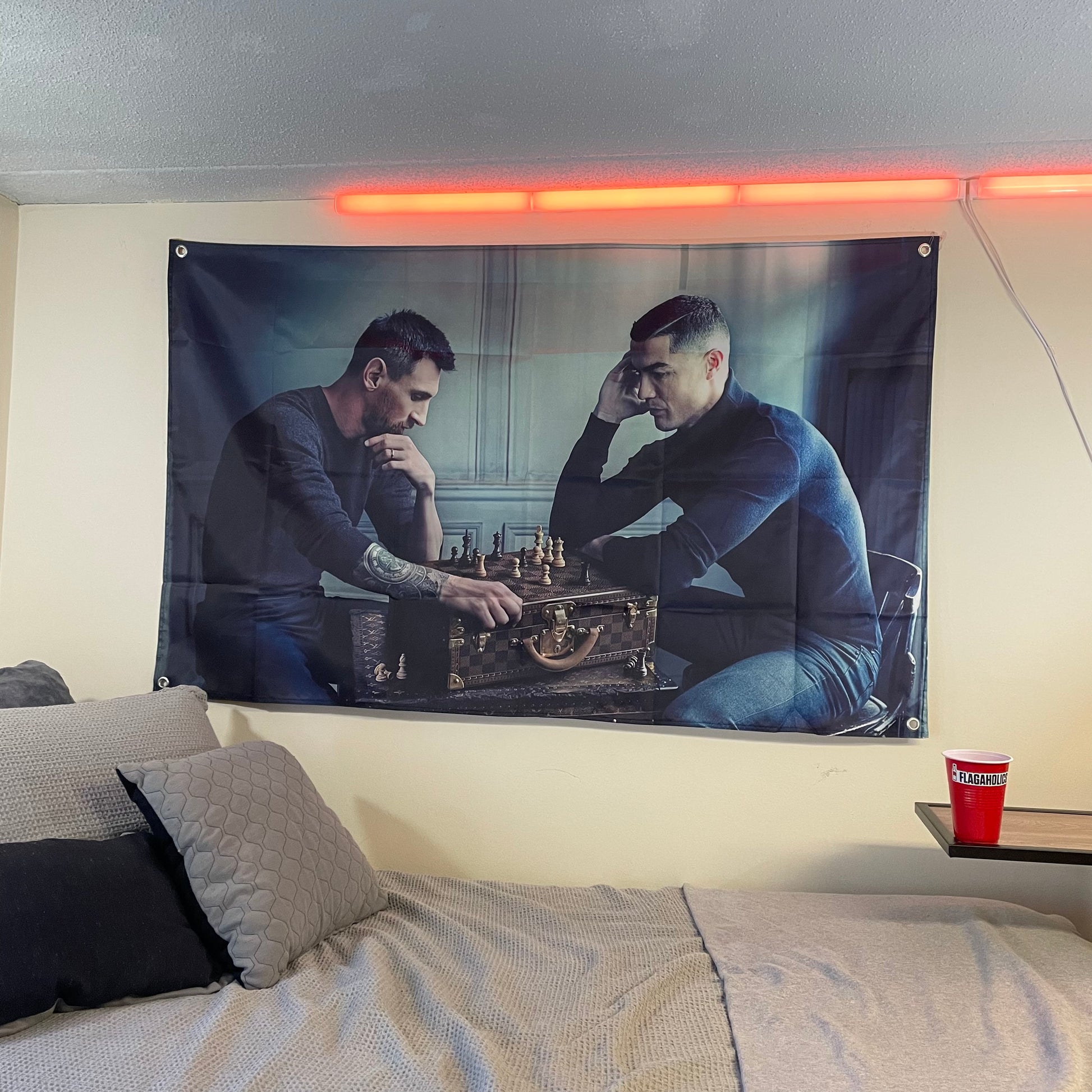flag of Lionel Messi and Christiano Ronaldo playing chess on a Louis Vuitton bag hung up in a college dorm room