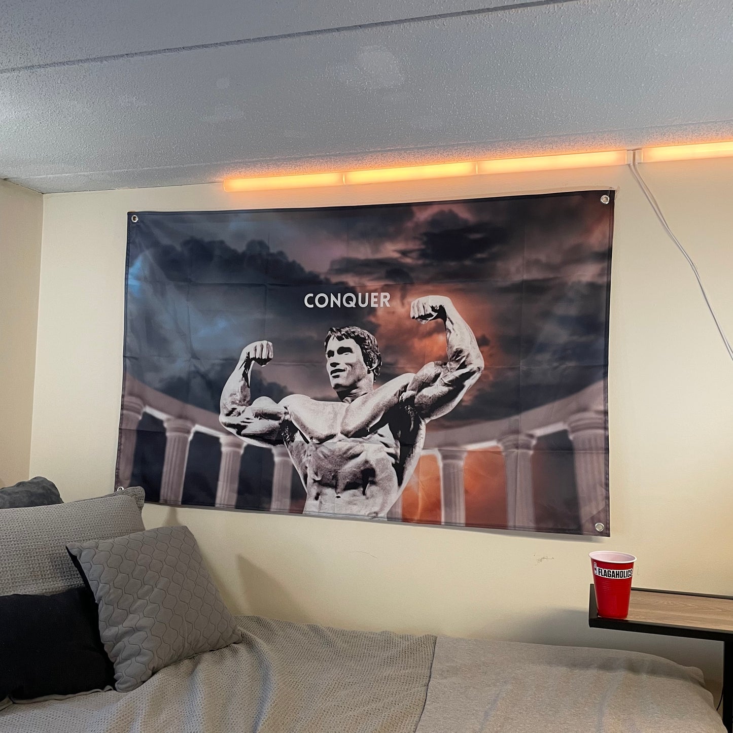 flag of Arnold Schwarzenegger with the word conquer hung up in a college dorm room