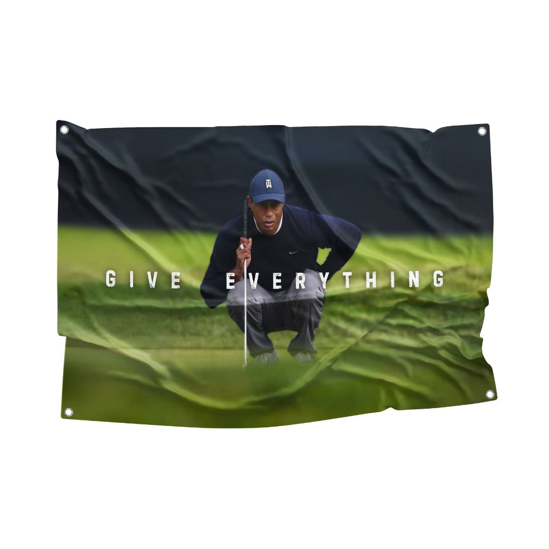 A motivational flag featuring a focused Tiger Woods in a crouched position on a golf course, with the words "GIVE EVERYTHING" displayed boldly across the center.