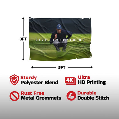 The "GIVE EVERYTHING" flag showcases a high-quality image of Tiger Woods printed on a sturdy polyester blend, equipped with ultra HD printing, rust-free metal grommets, and durable double stitching.