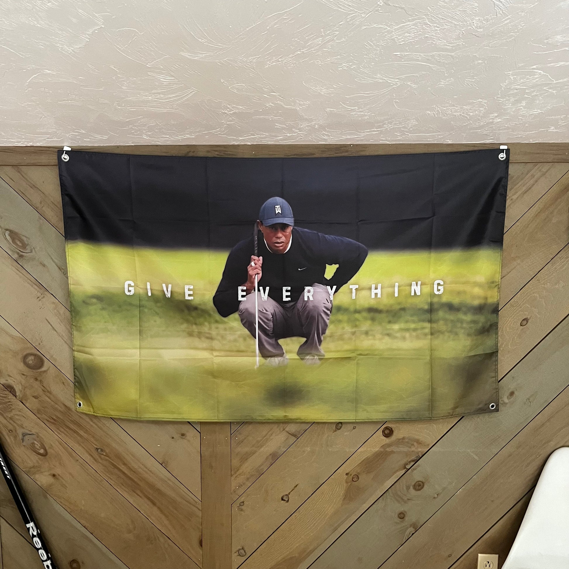 The "GIVE EVERYTHING" flag featuring Tiger Woods displayed in a room setting, adding a touch of inspiration and determination to any space, ideal for athletes and golf fans.